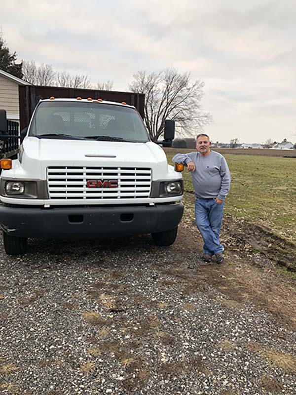 Wolfe Disposal and Hauling Service man standing with elbow on trash disposal truck